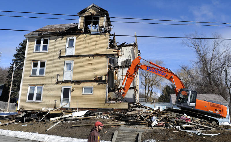 An excavator razes an apartment building at 1 Penobscot St. in Augusta Monday The four-story building was destroyed by fire Jan. 29.