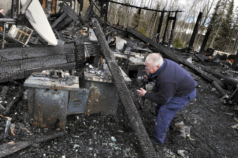 Investigator Ken MacMaster of the State Fire Marshal's Office examines machines in the cabinet shop of the Whitehouse residence in Mount Vernon Sunday. The building burned early Sunday morning.