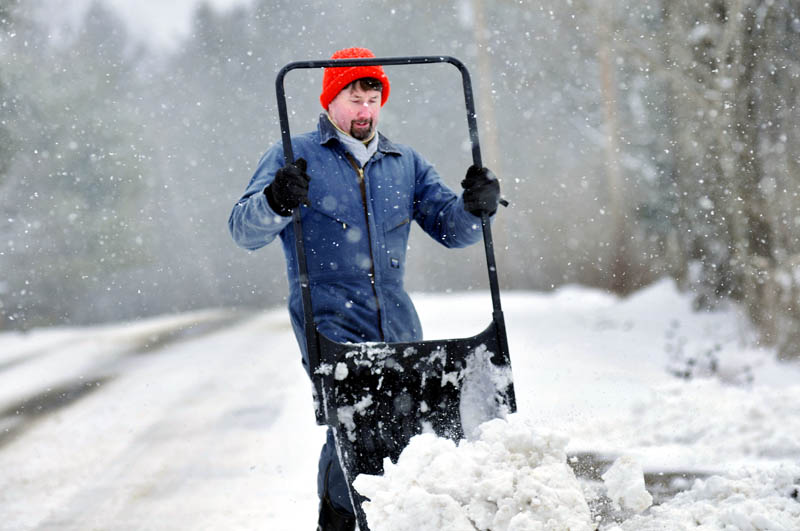 Kyle Smith kicks loose a bucket of snow Tuesday while clearing the drive of his West Gardiner home. "A year ago we were riding horses in T-shirts," Smith recalled, while collecting this winter's most recent deposit of snow.