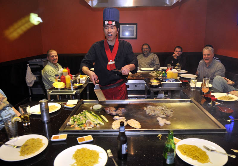 Chef Ricky Huang tosses a piece of broccoli into the mouth of a patron, as he prepares meals for the group at Mirakuya Steak House in Waterville Wednesday night.