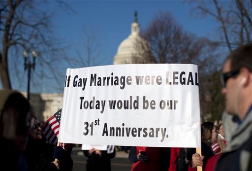 With the Capitol in the background, supporters of gay marriage carry signs in front of the Supreme Court on Wednesday, before the court began hearing arguments on a constitutional challenge to the law that prevents legally married gay Americans from collecting federal benefits generally available to straight married couples.