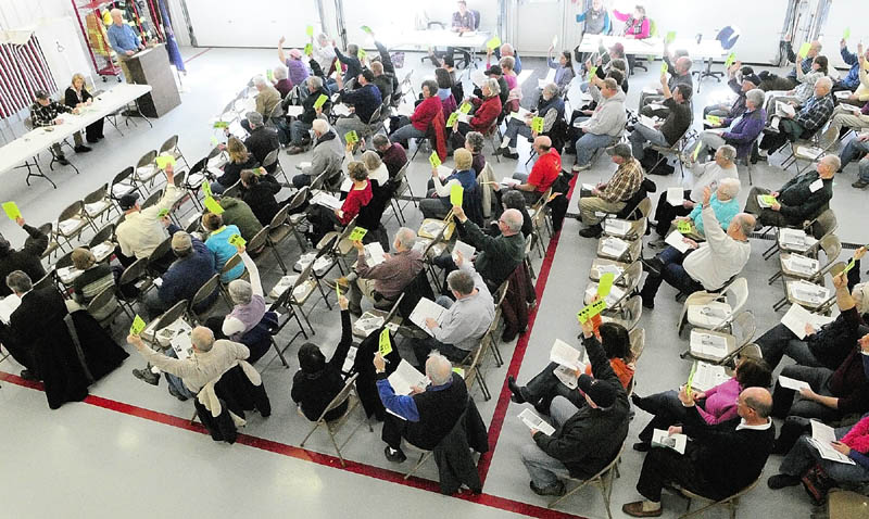 Selectman Merton Hickey, left, sits at the head table with Town Clerk Heidi Peckham, while Selectman Gregory Couture acts as moderator, as about 180 people vote on the town's business during the West Gardiner Town Meeting on Saturday.