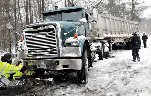 Tow truck workers prepare to haul a 2005 Freightliner tractor-trailer following a collision with a 2003 Ford Explorer on the Unity Road in Benton March 19.