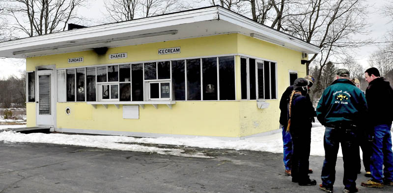 People gather outside the gutted Here's The Scoop ice cream shop, beside the Riverside Inn in Bingham ,on Sunday. Fire heavily damaged the interior of the building late Saturday.
