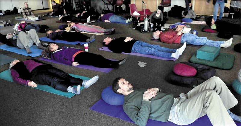 Western Maine Buddhism seminar presenter Jeb Enoch, foregrond, and participants prepare for meditation during the event on Sunday at the University of Maine in Farmington.