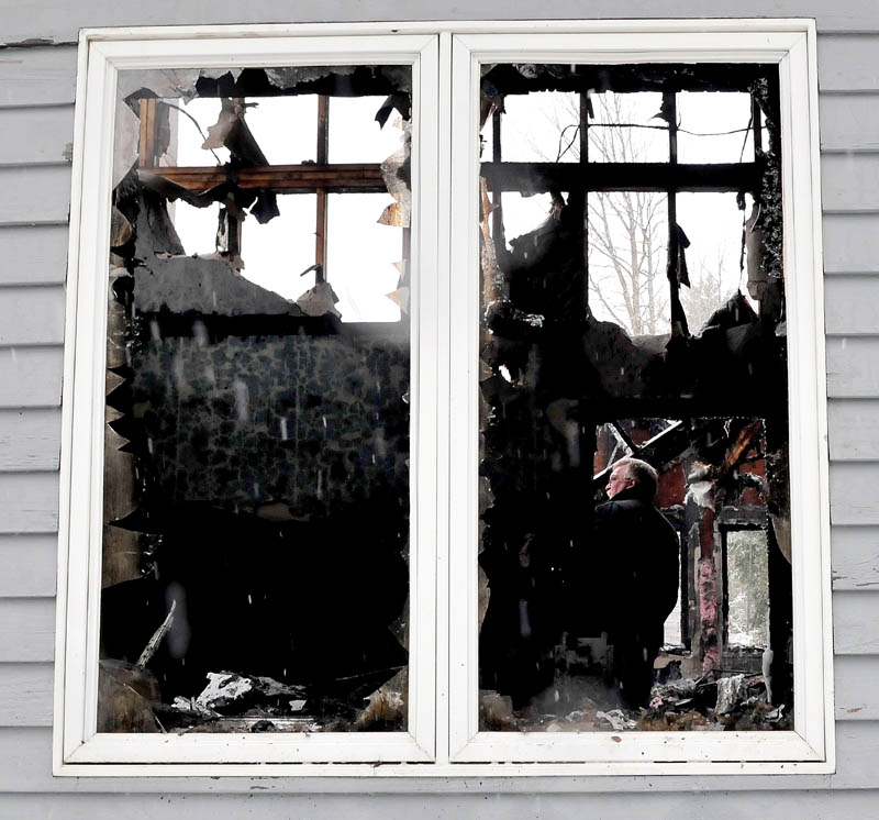 Stu Jacobs, an investigator with the State Fire Marshal's Office, searches for the cause of fire inside the burned remains of a house off U.S. Route 202 in Troy that was destroyed on Monday.