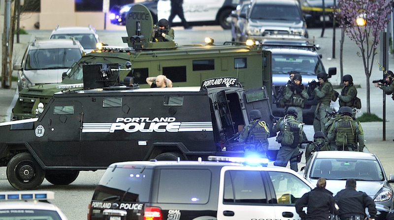 A suspect surrenders – surrounded by Portland police and SWAT Team members – after a standoff on Alder Street in Portland on Monday evening.