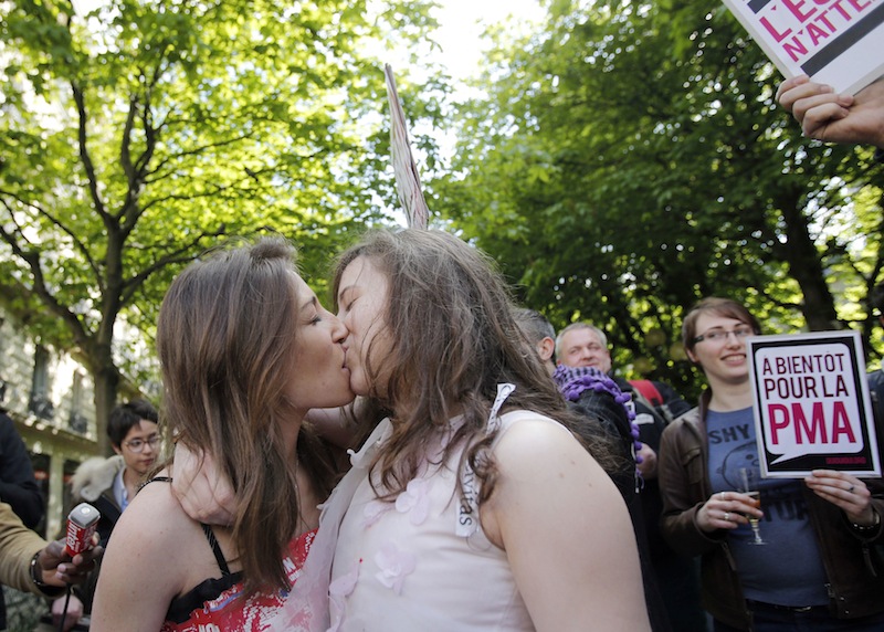 Pro gay marriage activists kiss after French lawmakers legalized same-sex marriage, Tuesday, April 23, 2013 in Paris. Lawmakers legalized same-sex marriage after months of bruising debate and street protests that brought hundreds of thousands to Paris. Tuesday's 331-225 vote came in the Socialist majority National Assembly. France's justice minister, Christiane Taubira, said the first weddings could be as soon as June. Poster rends: Medically Assisted Reproduction.(AP Photo/Christophe Ena)