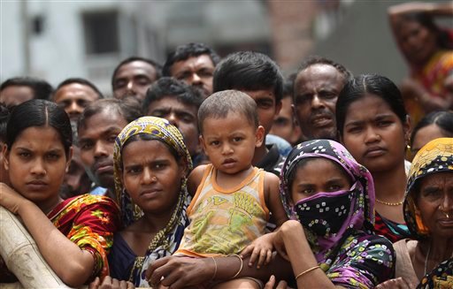 Curious onlookers and relatives of missing victims watch from behind a fence as workers start removing pieces of the garment factory building that collapsed in Savar, Bangladesh.