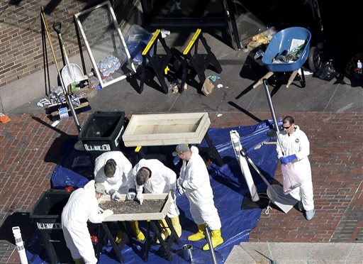 Investigators inspect the area between the two blast sites near the Boston Marathon finish line on Thursday in Boston. Boston remained under a heavy security presence, with scores of National Guard troops gathering among armored Humvees in the Boston Common.