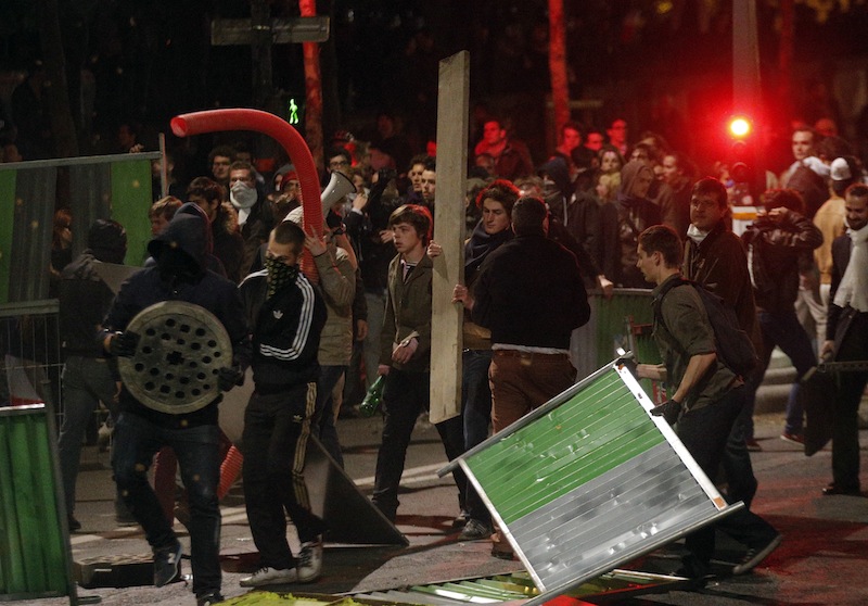 Demonstrators clashes with riot police, Tuesday, April 23, 2013 in Paris. Clashes break out near France's National Assembly building hours after the country legalized gay marriage. The 331-225 vote came after months of wrenching debate. France's justice minister say weddings could begin as early as June. Some protesters hurl glass bottles, cans and metal bars; police are responding with tear gas. (AP Photo/Christophe Ena)