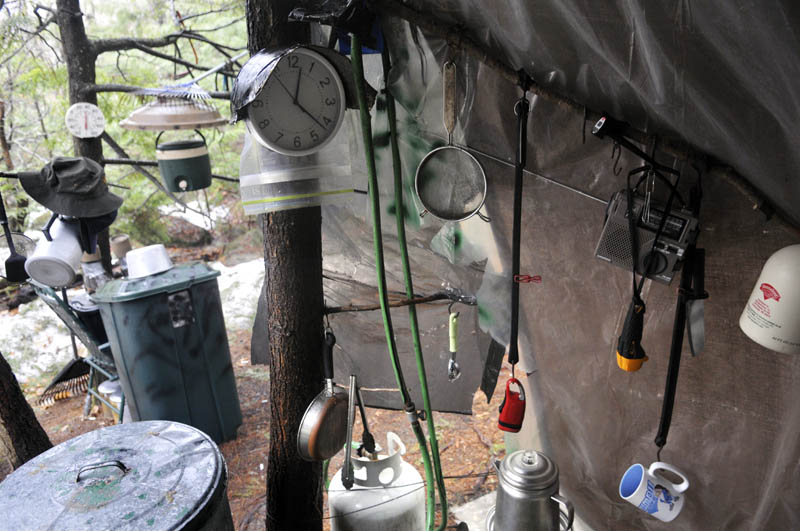 Staff photo by Andy Molloy Coffee cups, lights and a clock hang under a tarp in Christopher Knight's camp Tuesday April 9, 2013 in a remote, wooded section of Rome after police inspected the site where Knight is believed to have lived since the 1990s. Police believe Knight, who went into the woods near Belgrade in 1986, was a hermit who committed hundreds of burglaries to sustain himself. Knight apparently cooked meals with propane he stole, police claim.