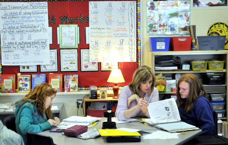 Karen Mayo, a fifth-grade teacher at the James H. Bean School in Sidney helps two students Jade Veillaux, 11, right, and Macey Eubank, 10, left, on Wednesday. James H. Bean is one school in the area that has implemented a mass customized learning program that integrates up to three grade levels in one classroom.