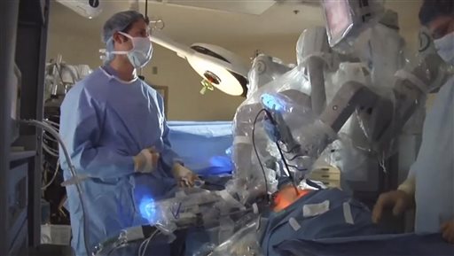 In this photo from video provided by Intuitive Surgical Inc. of Sunnyvale, Calif., maker of the da Vinci robotic system, doctors are seen using the device to perform a surgery. Surgeons say the advantages of the system include allowing them to operate sitting down, using small robotic hands with no tremor. But critics say a big increase in robot operations nationwide is due to heavy marketing and hype.