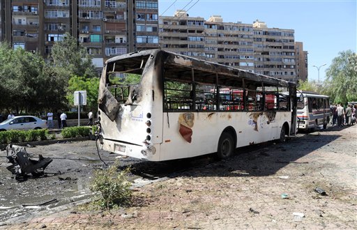 This photo released by the Syrian official news agency SANA, shows Syrians inspecting a damaged car at the scene of a car bomb exploded in the capital's western neighborhood of Mazzeh, in Damascus, on Monday. State-run Syrian TV says Prime Minister Wael al-Halqir has escaped unhurt in an assassination attempt when a bomb went off near his convoy.