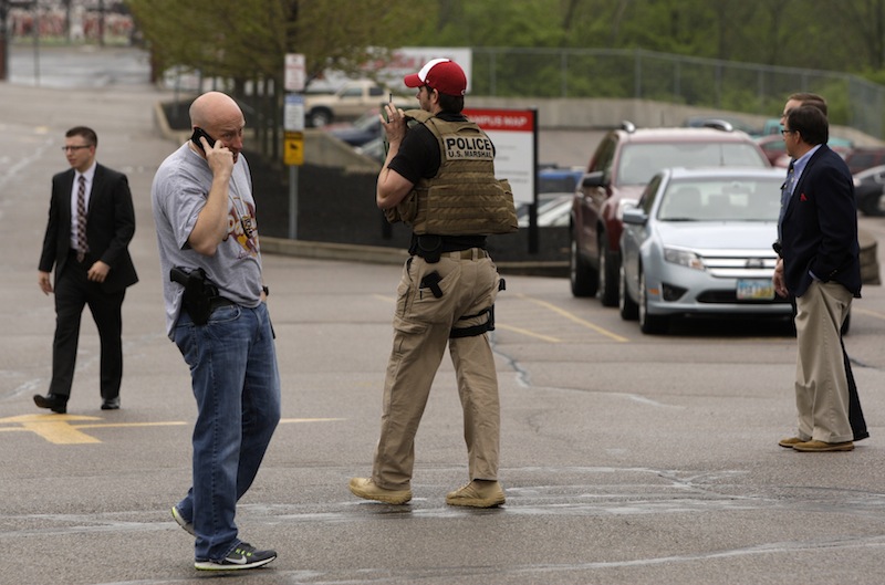 Sheriff's Deputies and other officials stand outside LaSalle High School, Monday, April 29, 2013, in Cincinnati where a high school student pulled out a gun and shot himself in a classroom on Monday. The Hamilton County sheriff's office says the youth was taken to a hospital with a self-inflicted wound. They say there apparently was no threat to other students at the private school. (AP Photo/Cincinnati Enquirer, Glenn Hartong)