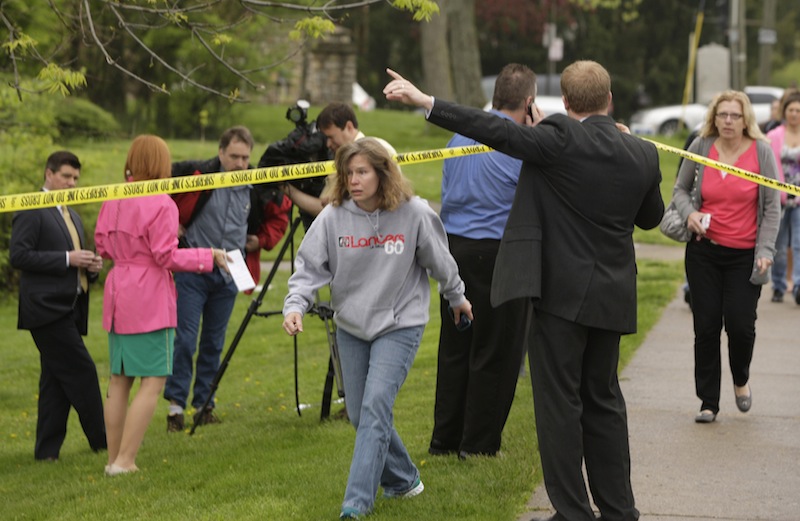 Parents and other family members cross under a police line to check on their children, Monday, April 29, 2013, at LaSalle High School in Cincinnati, where a high school student pulled out a gun and shot himself in a classroom on Monday. The Hamilton County sheriff's office says the youth was taken to a hospital with a self-inflicted wound. They say there apparently was no threat to other students at the private school. (AP Photo/Cincinnati Enquirer, Glenn Hartong)