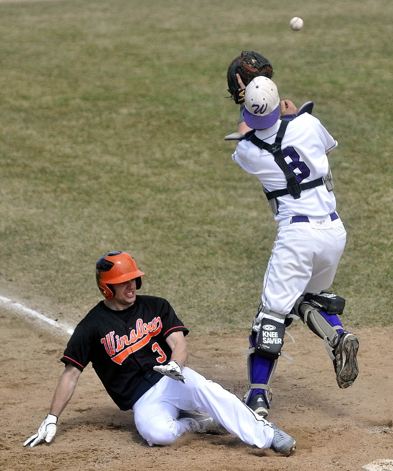 Staff photo by Michael G. Seamans Winslow High School's Donald Camp, 3, slides under Waterville Senior High School catcher Aidan Fitzgerald, 8, in the third inning in Waterville on Friday.