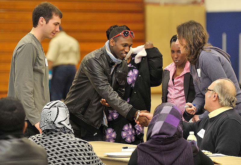 Josh Ntimugura from the congo shakes the hand of John Kavanaugh, father to Laragh Kavanaugh, right, a mentoring volunteer to Josh's sister, Jeanette, middle, as the large group of attendees met each other and found new friends in the community during New Mainers Day Saturday at the Sullivan Recreation and Fitness Complex on the USM Portland Campus.