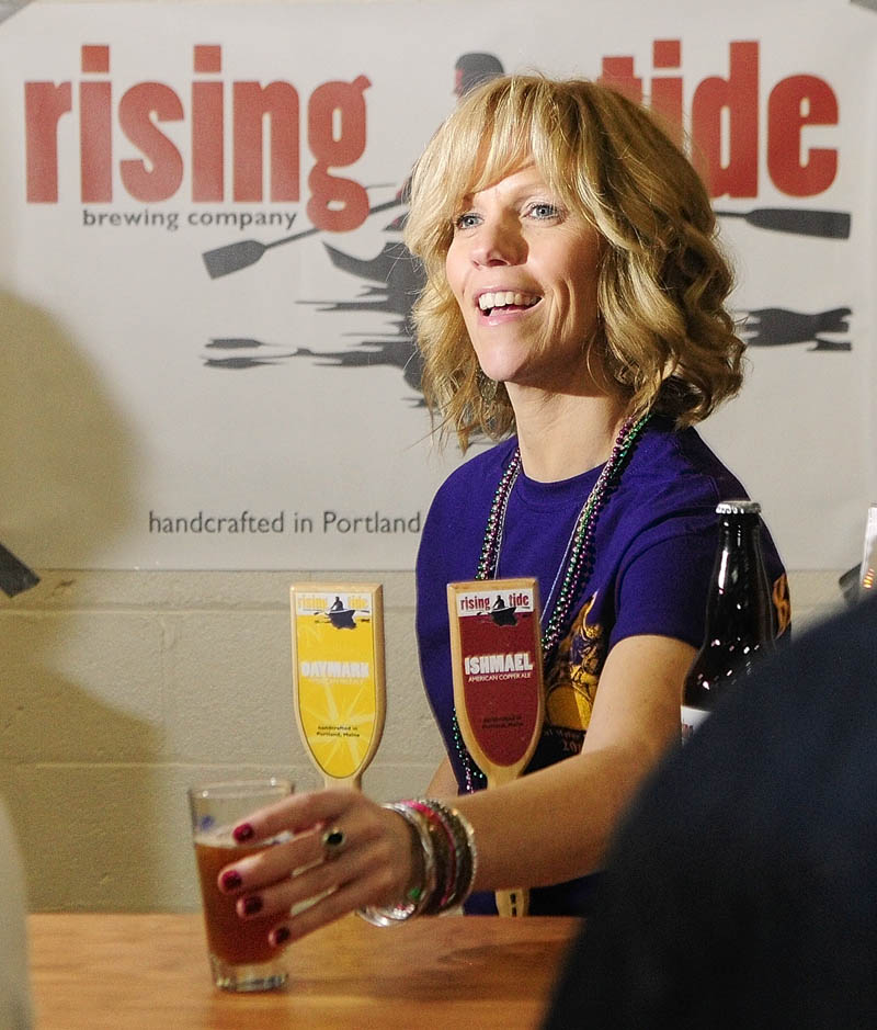 Volunteer pourer Penny Vaillancourt hands a glass of Ishmael American Copper Ale to a customer at the Rising Tide booth on Saturday during the Central Maine Brew Fest at the Augusta armory.