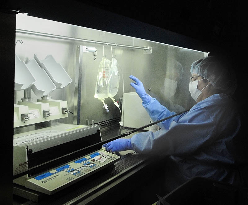 Pharmacy technician Suzanne Goddard works under a hood, preparing bags of intravenous medicines, in the sterile room on April 12 at Kennebec Pharmacy & Home Care in Augusta.