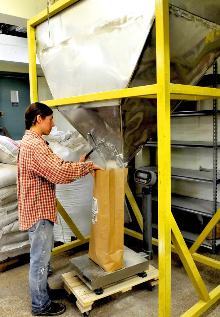 Head miller Julie Zavage bags flour pouring from a hopper at the Maine Grains business in Skowhegan on Thursday.