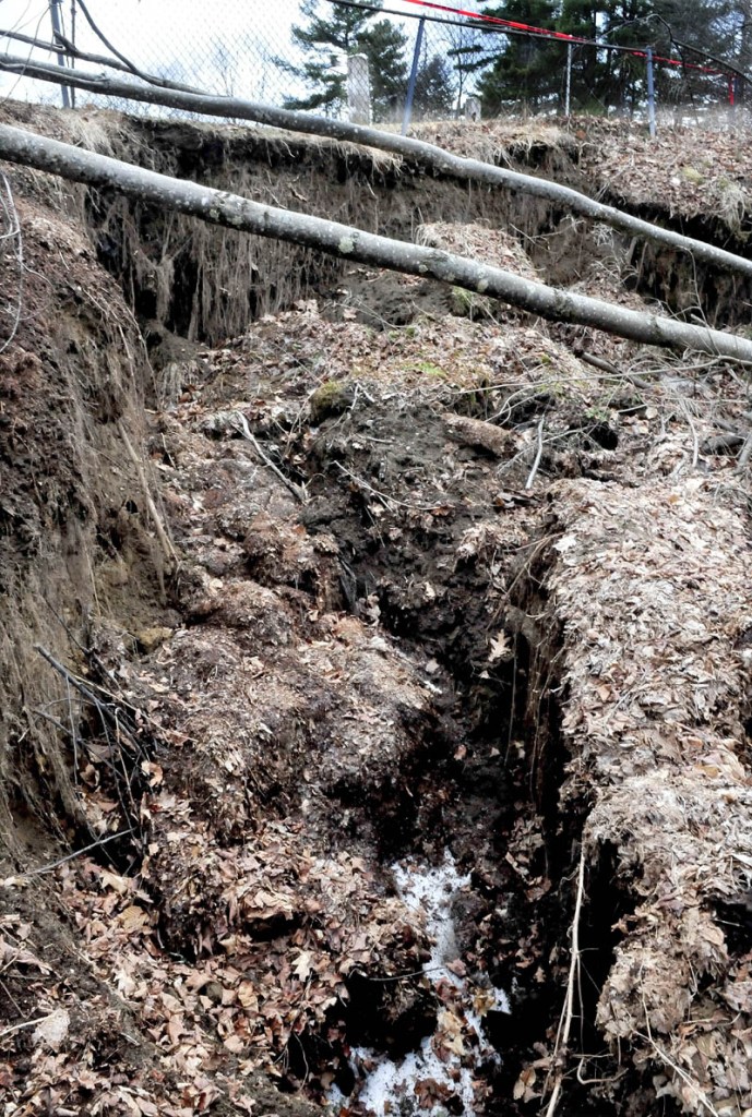 The ground, trees and shrubs have dropped from a steep slope near grave markers, top, at the North Cemetery in Skowhegan.