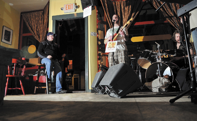 Sam Shain, center, plays the guitar while his brother, Josh, plays the drums with their band, The Scolded Dogs, at Higher Grounds in Hallowell Friday to an empty dance floor. The Office of the State Fire Marshal recently cracked down on establishments that permit dancing that don't meet code. The Scolded Dogs normally play to a packed house with several people dancing.
