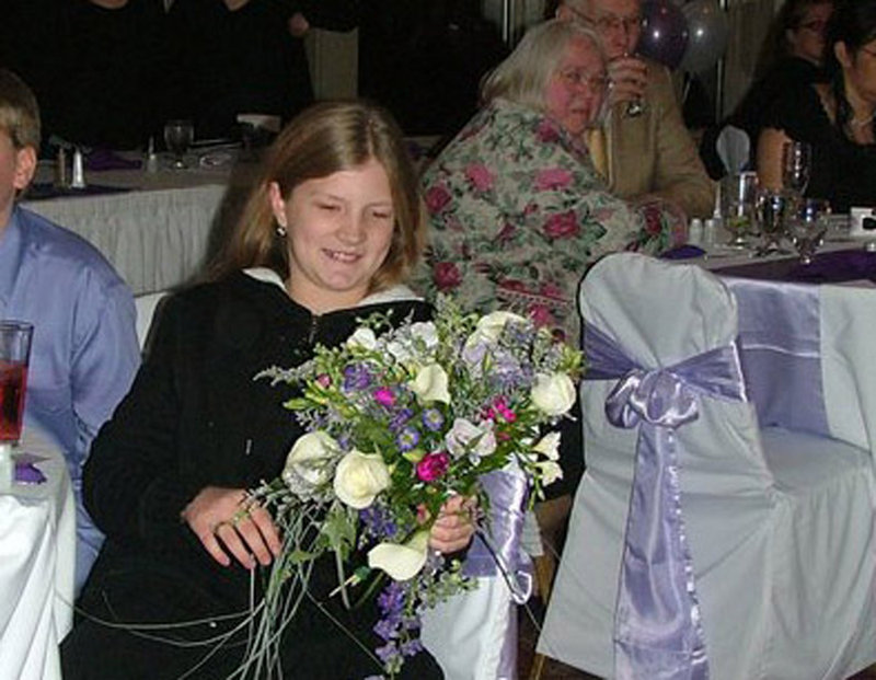 Kitty McGuire holds the bouquet she caught at the wedding of Timothy and Hannah McGuire three years ago. She was always the one who caught wedding bouquets, the couple said.