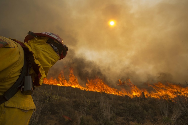 A firefighter keeps watch as the wildfire burns along a hillside in Point Mugu , Calif. Friday, May 3, 2013. Firefighters got a break as gusty winds turned into breezes, but temperatures remained high and humidity levels are expected to soar as cool air moved in from the ocean and the Santa Ana winds retreated. (AP Photo/Ringo H.W. Chiu)