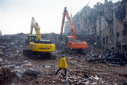 A rescue worker walks in the rain in the rubble of the garment factory that collapsed in Savar, Bangladesh.