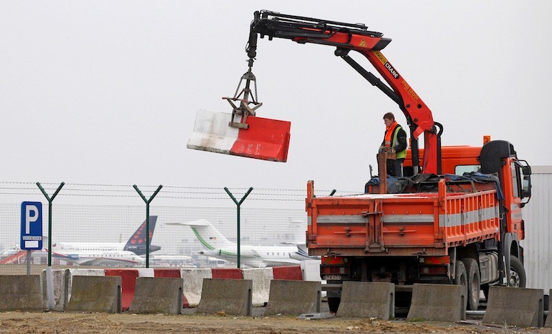 In this Feb. 19, 2013 file photo workers place concrete blocks to block access to a security fence next to the tarmac at Brussels international airport. Police carried out a series of raids on Wednesday, May 8, 2013, in Belgium and detained 31 people in three countries in connection with a spectacular $50 million diamond heist pulled off with apparent clockwork precision at Brussels Airport, a Belgian prosecutor said Wednesday. (AP Photo/Yves Logghe, file)