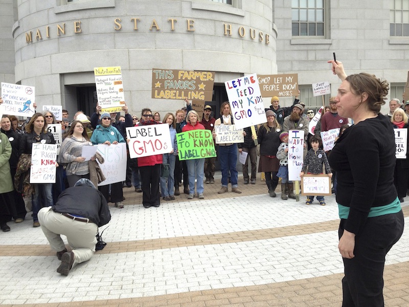 In this April 23, 2013 file photo, Logan Perkins of the Maine Organic Farmers and Gardeners Association, right, rallies supporters outside the State House for a bill that would require genetically modified products to be labeled. A legislative panel approved the bill 8-4 on Tuesday, May 14, 2013.