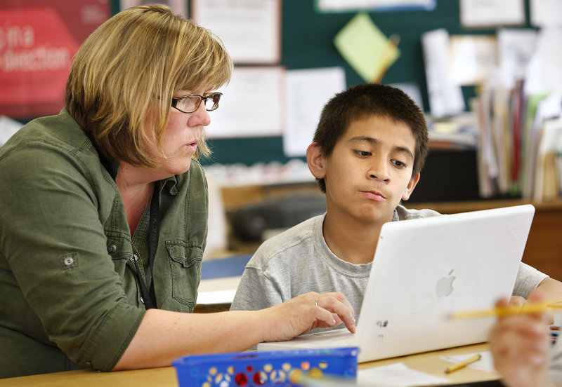 Sixth-grade teacher Lisa Hatch works with Emmanuel Iglesias Tuesday, May 27, 2013, on a laptop during class at King Middle School. The class uses laptops that are seven or eight years old.