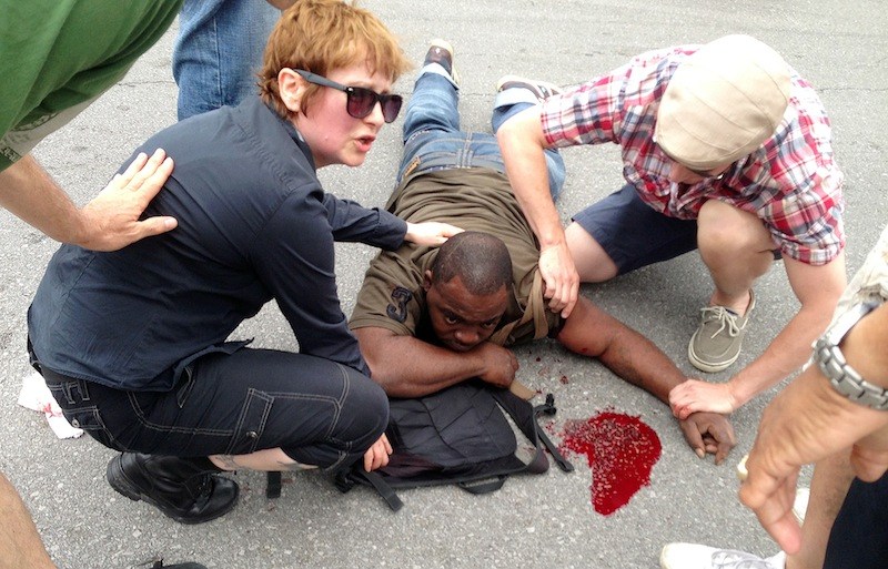 Bystanders comfort a shooting victim while awaiting EMS at the intersection of Frenchmen and N. Villere Streets after authorities say gunfire injured at least a dozen people, including a child, at a Mother's Day second-line parade in New Orleans on Sunday, May 12, 2013. No deaths were reported. (AP Photo/The Times-Picayune, Lauren McGaughy)