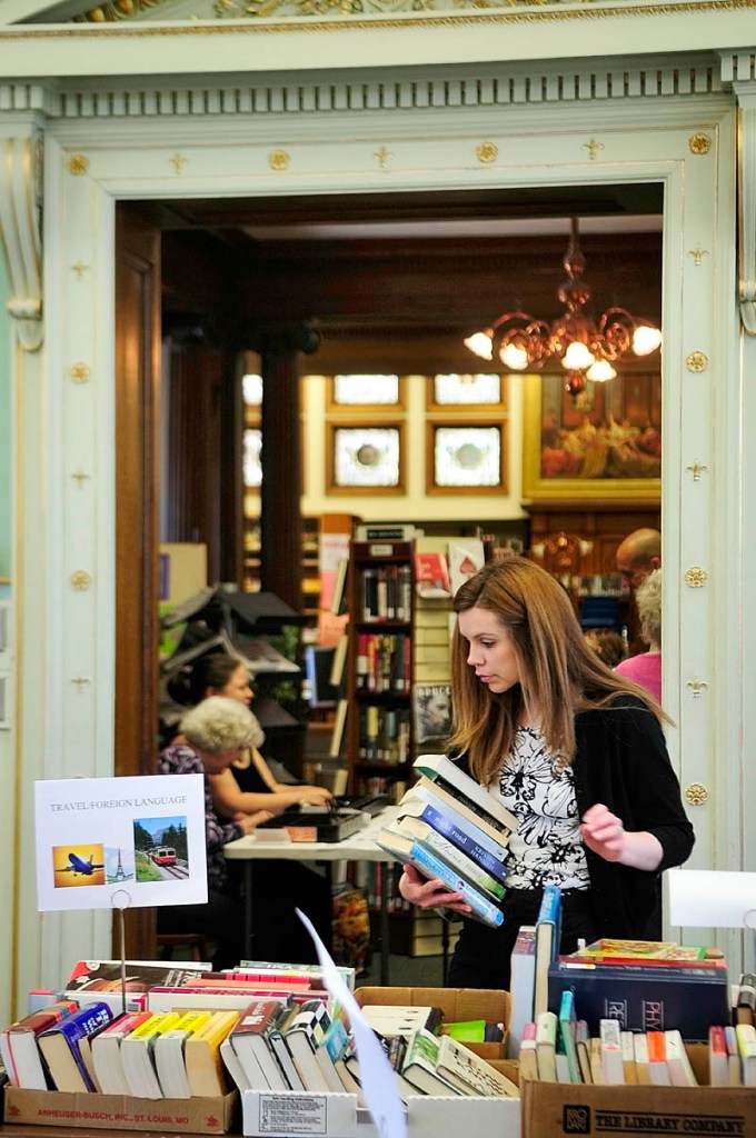 Kelly Houston searches for more used books to buy on Thursday in the Reading Room at the Lithgow Public Library in Augusta. The book sale continues Friday from 9 a.m. to 4 p.m. and then on Saturday from 9 a.m. to noon. They're planning on having two sales a year inside the library instead of one big one at an offsite venue.