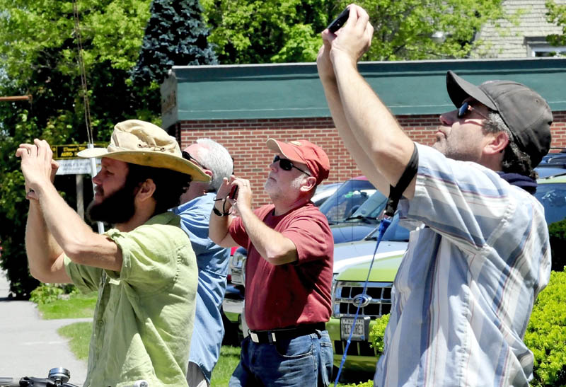 Onlookers, including Dave Begin, center, watch and photograph the cross and steeple removal on top of St. Francis de Sales Catholic Church in Waterville on Tuesday.