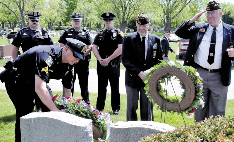 Waterville police Sgt. Lincoln Ryder lays a wreath for fallen law enforcement officers during a wreath-laying ceremony for veterans, firefighters, police and emergency workers on Sunday at the St. Francis and Pine Grove cemeteries in Wateville.