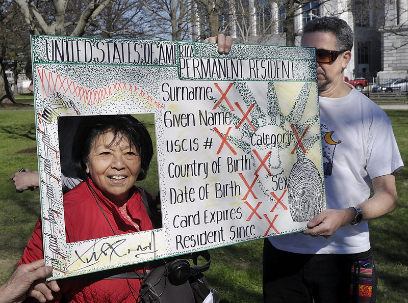 A variety of groups in Portland marched in support of immigration reform from Lincoln Park to Monument Square on Wednesday, May 01, 2013. Before the march, Victoria Chicon, a member of the group Nosotros We the People gets her picture taken by a friend. On the right, Orlando Andrew from Chile – a member of the Latin Center for Latino immigrants – holds an artist's rendition of a permanent resident card.