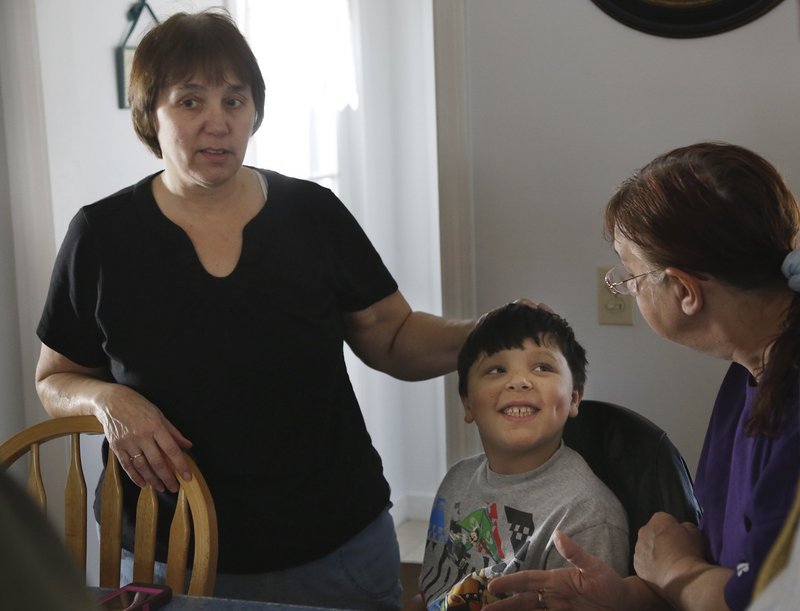Ja'kai Hayden, 8, smiles while spending time with his grandmother Patricia Gerber, left, and relative Paula Beaulieu during a family gathering in Portland.