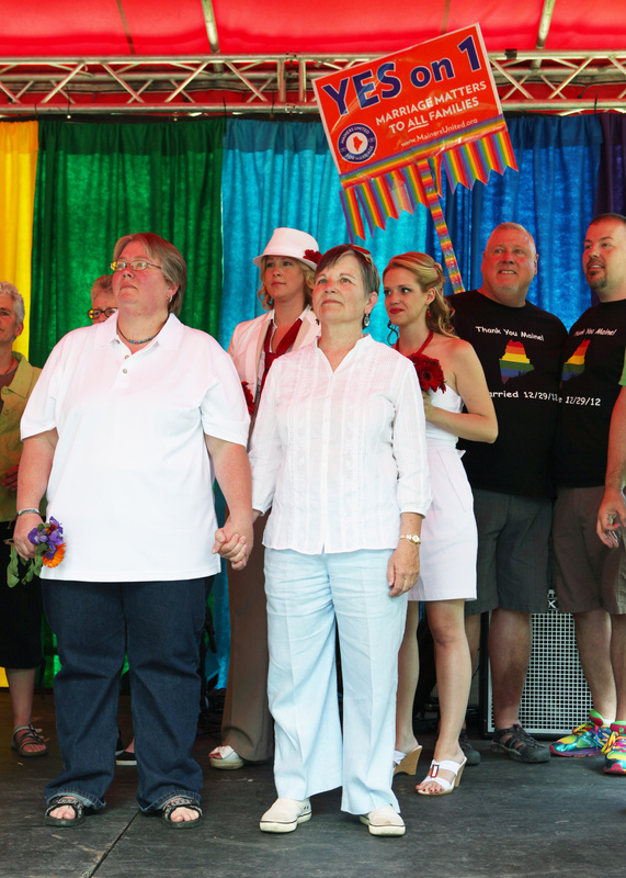 Chris Andre, left, and Chris Fleuriel, right, listen to the officiant during a mass wedding held Saturday in Deering Oaks park in Portland. Behind them are Stephanie Ginn and Sara Ginn, and Michael Snell and Steven Bridges. Bridges and Snell were the first couple to be married in Portland after same-sex marriage was legalized in 2012.
