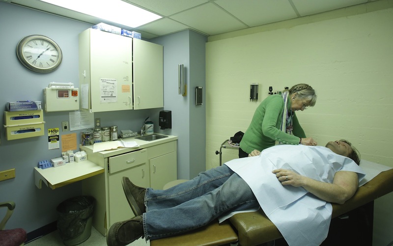 In this December 2012 file photo, Peggy Akers, a nurse practitioner who volunteers at the India Street Public Health Clinic in Portland, examines Charles Lafland during a physical exam at the clinic. Gov. Paul LePage vetoed a Medicaid-expansion bill on Monday, June 17, 2013, denying 60,000 low-income Mainers health care under the Affordable Care Act.