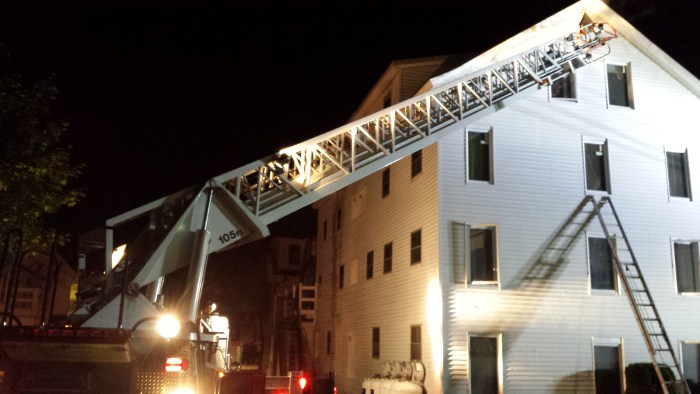 The Augusta Fire Department's ladder truck is extended to a ventilation hole cut into the rear of an apartment house at 26 Sewall St. in Augusta late Saturday.