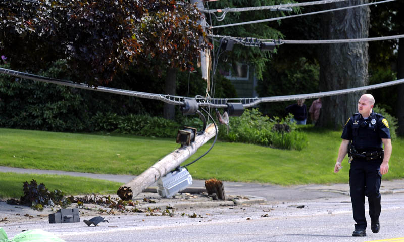 Augusta Police Department Officer Nathan Walker walks past the utility pole that was snapped Monday on Hospital Street, by a car driving in the north lane. A passenger of the vehicle was transported to the hospital following the accident, which was reported just after 2 p.m., according to Walker. The driver, Andrew Pinkham, 34, of Bath, was charged with operating a vehicle after suspension, Walker said.
