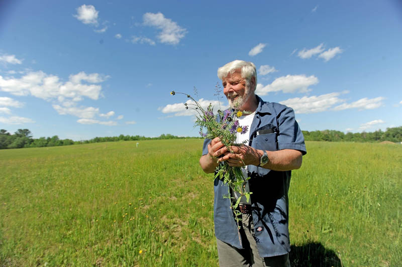 Johnny Thomas stands with some native flowers growing on top of the dump at the Oakland transfer station on Wednesday.