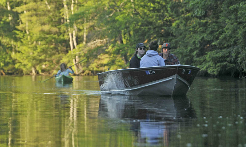 Boaters pass Christine Keller as she paddles along the Serpentine waterway, a three-mile waterway that cuts across a peat bog as it connects East Pond and North Pond, on Thursday.