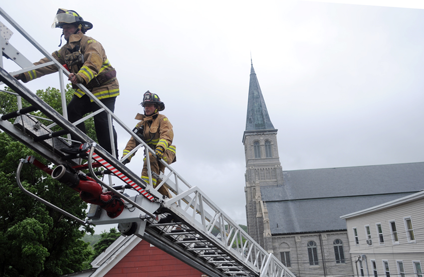 Augusta Police Officer Donald Whitten, left, and Firefighter Shawn Stevens scale a ladder to search the roof of an apartment building on York Street on Wednesday morning for stabbing suspect David Delesline, 44. Delesline is being sought for the Sunday morning assault on a 35-year-old woman at a York Street apartment where he allegedly returned Tuesday evening, according to Augusta Police Lt. Christopher Massey.
