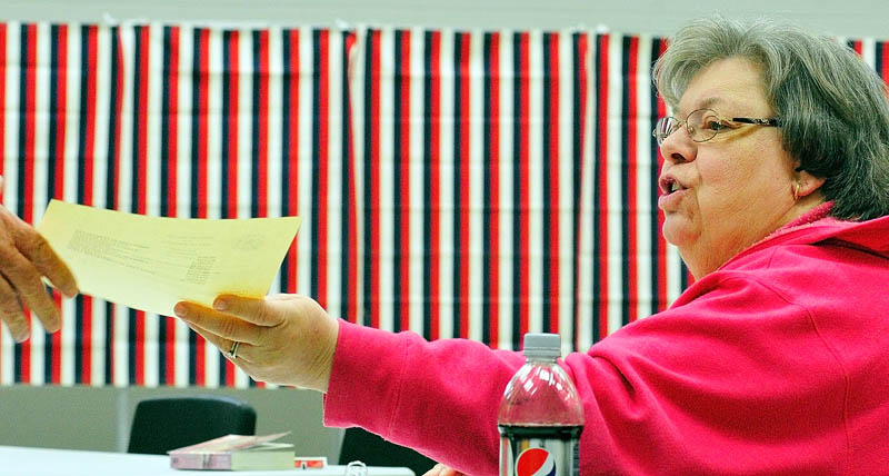 Ballot clerk Jeanine Gotreau hands a ballot to a voter on Tuesday at the Ward 4 polling place in the Cony Middle School music room in Augusta.