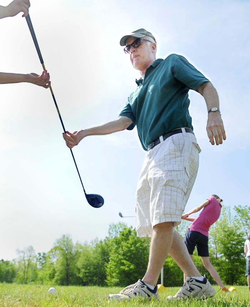 St. Michael teacher John Hickey hands a driver back to a student during a class golf outing on at Western View Golf Club in Augusta on May 31.