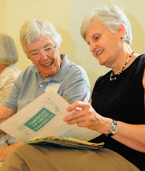 Audrey Fickett, left, looks at Melanie Lanctot's photo albums during a reunion for students of the town's one-room schoolhouses, on Friday at Asa Gile Hall in Readfield. Fickett, the mother of three of Lanctot's grade school classmates, worked in the cafeteria at the Readfield Elementary School that replaced the several smaller schools in the town.